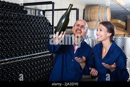 man and women winemakers with wine bottle. Stock Photo