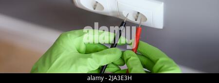 Measuring voltage with a multimeter, hands in rubber gloves Stock Photo