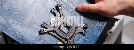 A man holds a motherboard over a pc, close-up Stock Photo