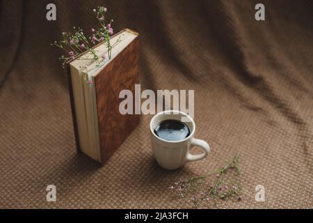 A book with flowers and cup of coffee on dark background top view Stock Photo