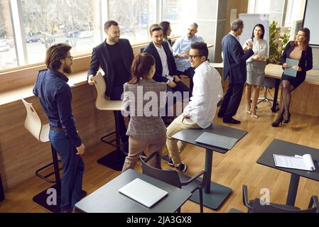 Friendly diverse employees or office workers communicating, talking and joking during break. Stock Photo