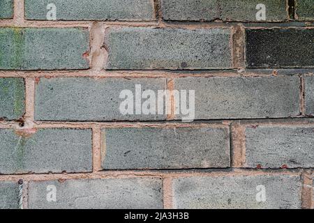 Image of rough briicks on the wall in a city centre. The texture shows bricks that are weathered and worn. Stock Photo