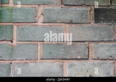 Image of rough briicks on the wall in a city centre. The texture shows bricks that are weathered and worn. Stock Photo