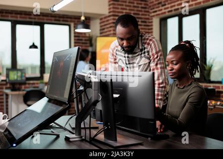 Software company employees brainstorming design ideas while sitting in office workspace. Creative agency production department workers trying to solve development issues of 3D project. Stock Photo