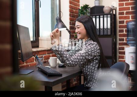 Happy motivated office worker satisfied by good results of promoting campaign. Overjoyed project manager celebrating job promotion and successful deal by vigorously raising fist. Stock Photo