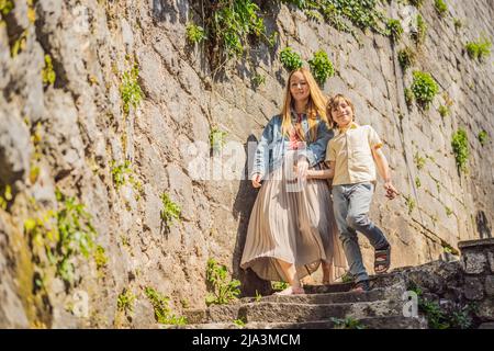 Mom and son tourists enjoying Colorful street in Old town of Perast on a sunny day, Montenegro. Travel to Montenegro concept. Scenic panorama view of Stock Photo
