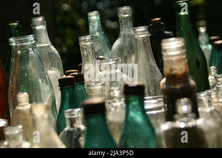 Russia, Izborsk Open Air Museum. June 16 2017. Exposition  of the Multicolored Antique Vintage Retro glass bottles in the courtyard of an old house. Stock Photo
