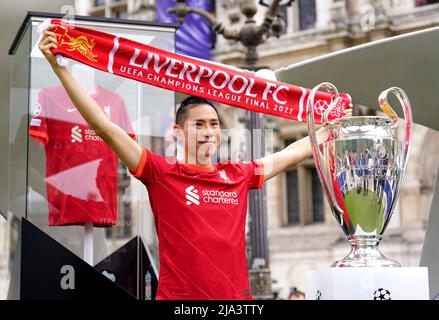 A Liverpool fan poses next to the UEFA Champions League trophy at the Trophy Experience at The Place de l'Hotel de Ville in Paris ahead of Saturday's UEFA Champions League Final at the Stade de France, Paris. Picture date: Friday May 27, 2022. Stock Photo
