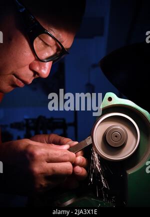 (220527) -- XINMI, May 27, 2022 (Xinhua) -- Cheng Yucai grinds tools at his workshop in Xinmi City, central China's Henan Province, on May 24, 2022.  Guilloche is a decorative technique in which a precise, intricate and repetitive pattern is mechanically engraved into a material via engine turning. The technique uses a machine controlled by the delicacy of the hand of craftsman. As an important process in making superior watch and jewelry, the art is now mastered by rarely few people.    Cheng Yucai, born in 1978, got to know Guilloche in 2013 when he saw a cigarette case decorated with the te Stock Photo