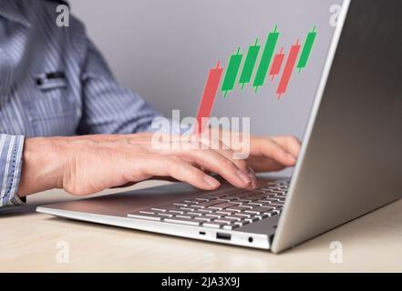 Man using candlestick graph for tracking price movement. Trader hands at laptop keyboard. Stock market analysis, investment, finance concept. High quality photo Stock Photo