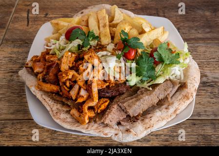 Mixed meat kebab with chips on nan bread, fast food for home delivery, takeaway or eat in. Stock Photo