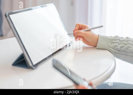 Close-up of woman working with stylus and digital tablet pc. Close up business woman hand using electronic or stylus pen, work on digital tablet at ho Stock Photo