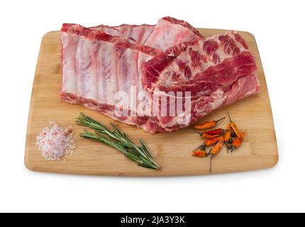 Raw pork ribs with spices, salt and rosemary on wooden background. Pork Ribs with rosemary, raw meat, close-up, isolated on white background. Stock Photo