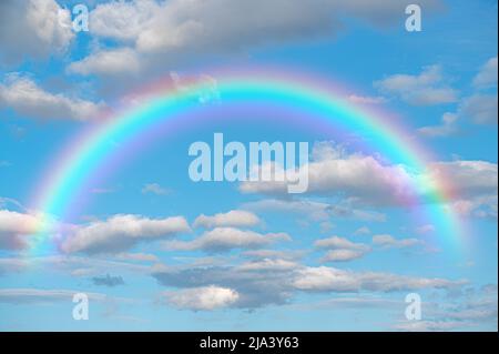 Rainbow Sky. Stunning blue sky rainbow big fluffy clouds with giant arcing rainbow against beautiful summer time blue sky with copy space for messages Stock Photo