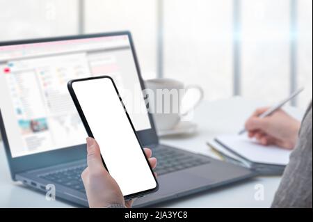 Mockup cellphone. Woman hand holding phone with blank screen in modern office. businesswoman using smartphone with blank screen at workplace desk. Stock Photo