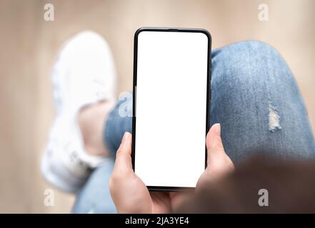 Top view mockup image of woman holding mobile phone with blank white screen. mockup image of woman using cellphone with while sitting on sofa Stock Photo