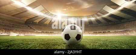 Traditional soccer football ball on grass of football field at stadium with spotlight. Concept of sport, art, energy, power Stock Photo