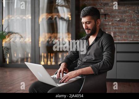 owner of a wine business working on a laptop in his shop . Stock Photo