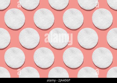 Regular seamless pattern of cotton cotton pads. Hygiene, body care. Flat lay minimal concept on a pink background. Directly above. Stock Photo