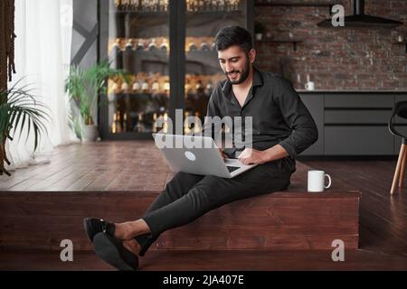 new business owner using a laptop while sitting on the floor. Stock Photo