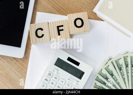 top view of dollar banknotes near calculator and cubes with cfo lettering Stock Photo