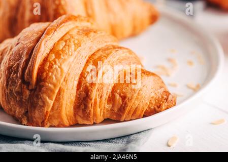 Plate with fresh croissants on white wooden table. Stock Photo