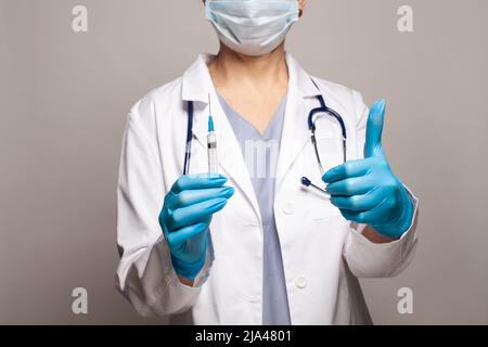 Doctors hands with injection, doctor holding syringe and showing thumb up Stock Photo