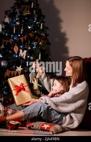 Happy family open Christmas lighting gift box near Christmas tree