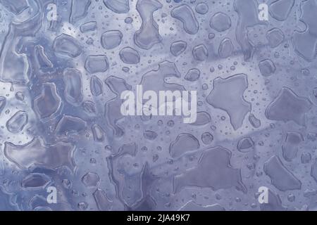 Close-up water drops pattern on glass surface abstract background. Toned purple image in trendy color of 2022. Copy space. Stock Photo