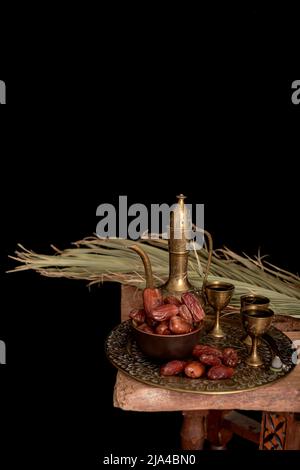 Ramadan Kareem Festive, close up of dates on wooden plate and rosary with oriental Lantern lamps and cup of black tea on wood background. Islamic Holy Stock Photo