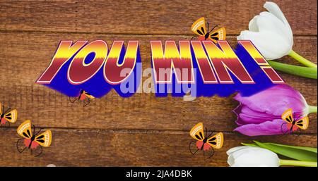 Image of you win text in red and blue letters over butterflies and tulips on wooden background Stock Photo