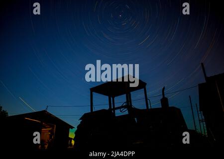 Time interval stars on the background of an old tractor and a house Stock Photo