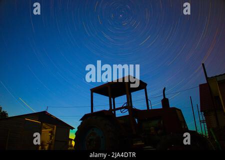 Time interval stars on the background of an old tractor and a house Stock Photo