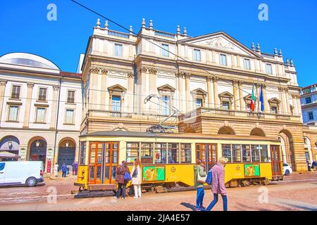 MILAN, ITALY - APRIL 5, 2022: The retro styled yellow tram rides along the facade of La Scala theater, on April 5 in Milan, Italy Stock Photo