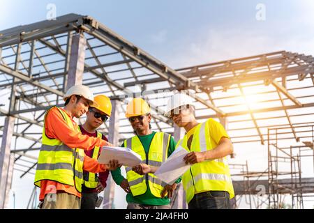 4 Workers in Construction Site, Engineer technician and Architect watching team of Workers Construction concept at Construction Site with blue print. Stock Photo