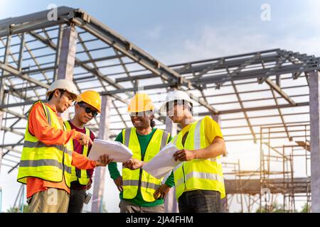 4 Workers in Construction Site, Happy of Engineer technician and Architect use blue print Planing together before starting work. Teamwork Concept. Stock Photo