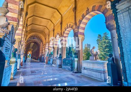 MILAN, ITALY - APRIL 5, 2022: The covered gallery with stone tombs of Monumetal Cemetery, on April 5 in Milan, Italy Stock Photo