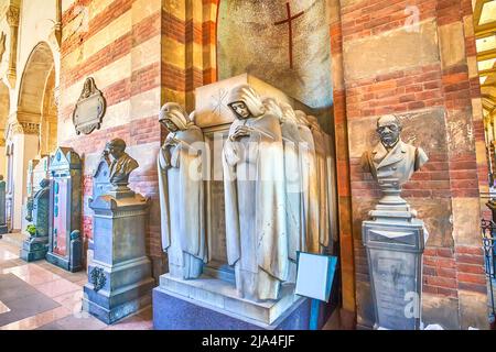 MILAN, ITALY - APRIL 5, 2022: The tomb with scenic sculptures in the loggia of Monumental Cemetery, on April 5 in Milan, Italy Stock Photo