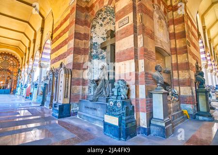 MILAN, ITALY - APRIL 5, 2022: The covered loggia with stone carved tombs, Monumental  Cemetery, on April 5 in Milan, Italy Stock Photo