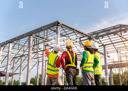 4 Workers in Construction Site, Contractor with workers and Steel roof structure under construction background. Stock Photo