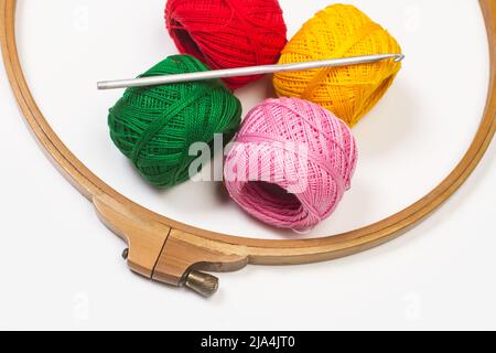 Colored yarn spools and a crochet hook on a white background Stock Photo