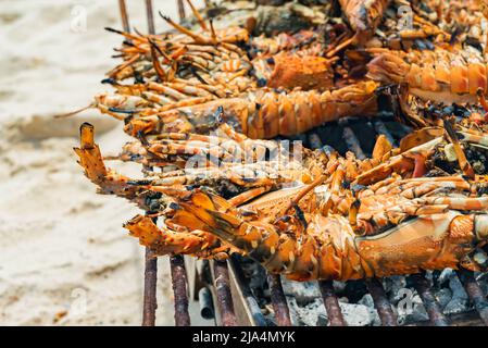 Grilled Lobster Cook on Charcoal Stove on sand beach, Zanzibar, Tanzania Stock Photo