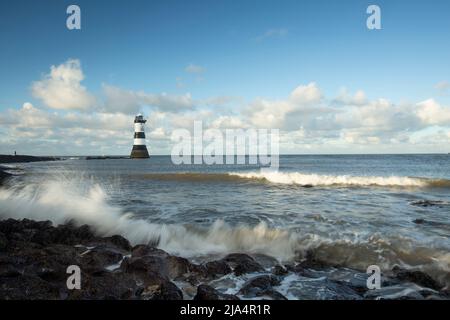 Trwyn Du Lighthouse, also known as Penmon Lighthouse, amid the crashing waves of the blue sea, Beaumaris north wales