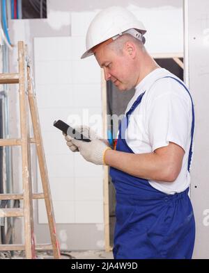 Smiling workman using phone Stock Photo
