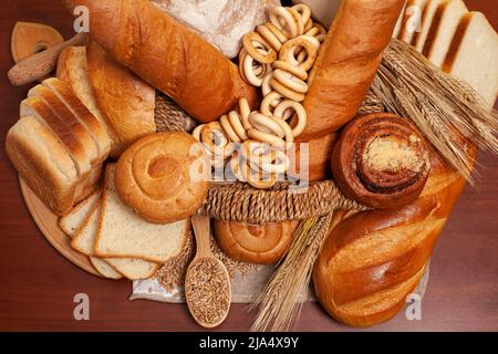 Culinary background with bread,buns,drying bagels,wheat ears,grains in a wicker basket,on a wooden table top view. Stock Photo