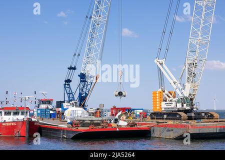 Lelystad, The Netherlands - April 22, 2022: Crane ship and supply vessel busy with demolition old offshore wind turbine Stock Photo