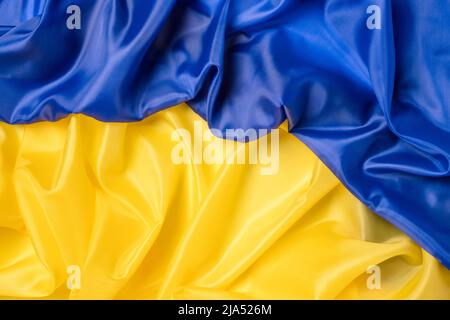 Fabric flag of Ukraine. Curved Ukrainian flag with ripples and material texture. National blue and yellow colors. Flat lay background, close up from Stock Photo