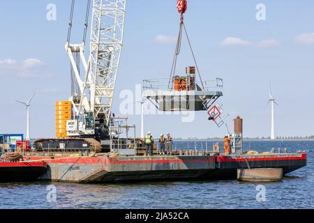 Lelystad, The Netherlands - April 22, 2022: Crane ship lifting foundation by demolition old offshore wind turbine Stock Photo