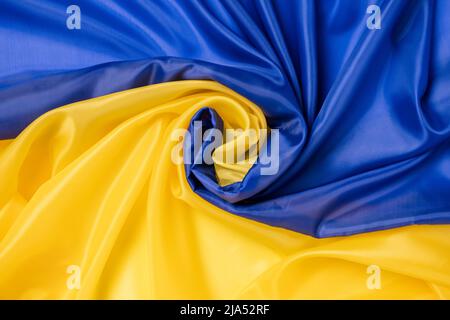 Fabric flag of Ukraine. Curved Ukrainian flag with ripples and material texture. National blue and yellow colors. Flat lay background, close up from Stock Photo