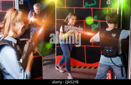 Children and parents aiming laser guns at other players during l Stock Photo